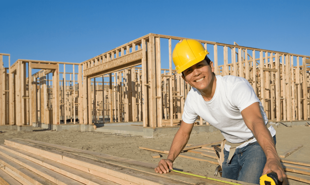 Construction worker measuring lumber on jobsite