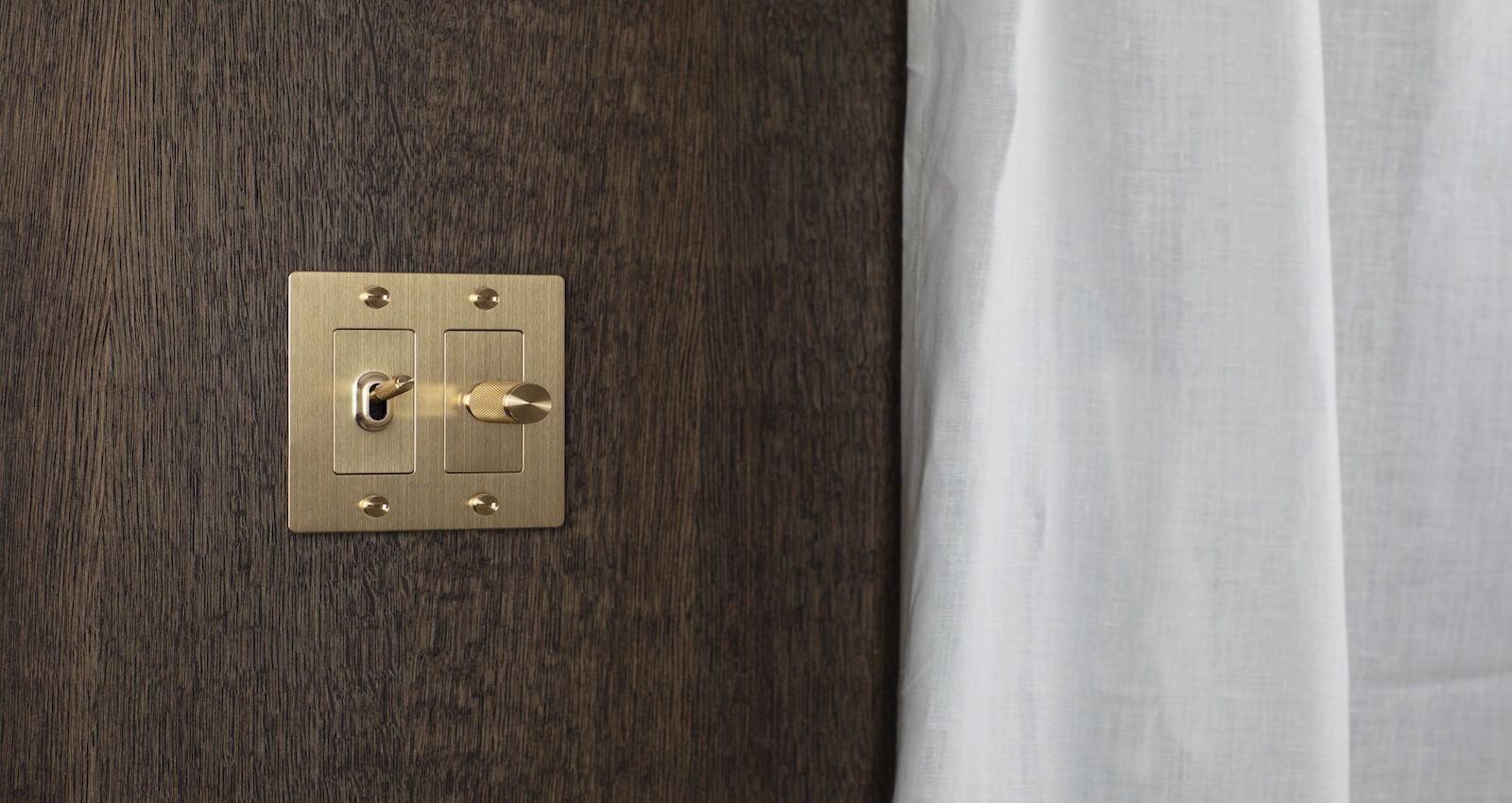 Brass light dimming switch on dark wood wall