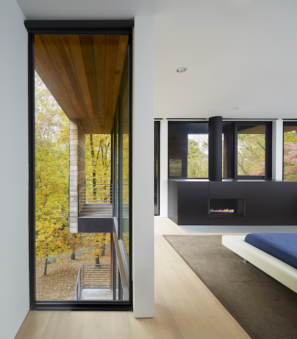 Floor-to-ceiling window in corner of master bedroom; views of woods