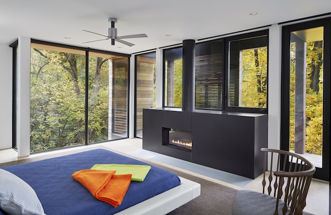 Master bedroom with large windows and black linear fireplace