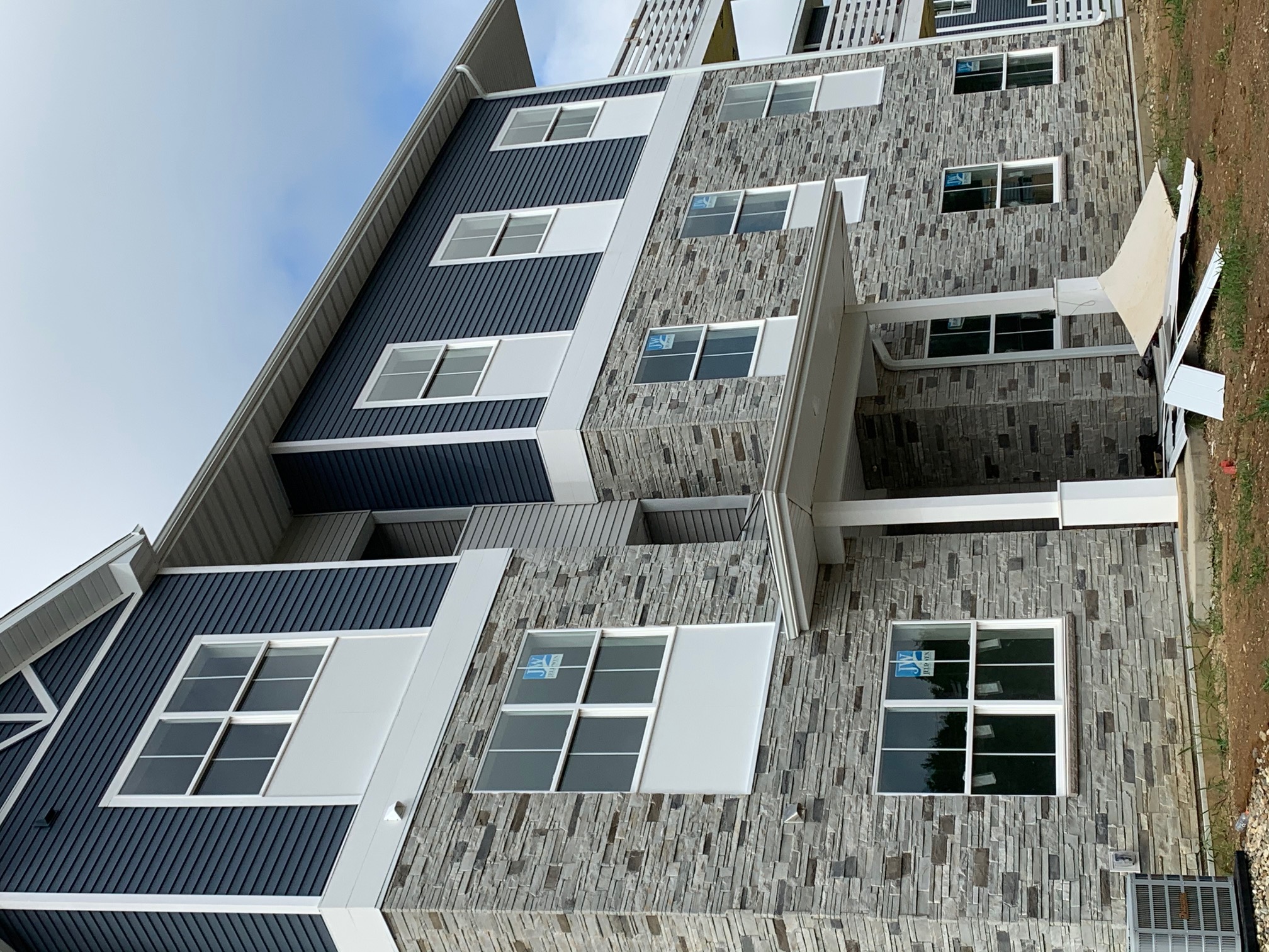 Versetta Stone siding and blue vinyl siding to lend a single-family feel that elevates this garden-style apartment complex