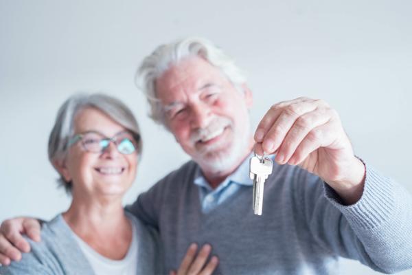 close up of mature man and woman holding a key of a new home