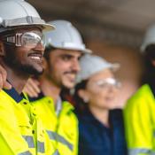 Profile view of four construction workers standing together and smiling