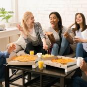 Members of Gen Z sit around coffee table laughing and sharing a meal 