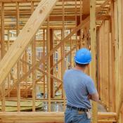 A home builder looks over at framing on new-construction home