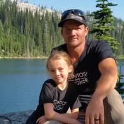 Man and daughter wearing matching shirts by a lake