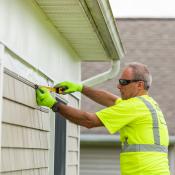 Construction worker measuring exterior trim of house
