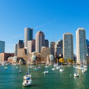 Sailboats in Boston harbor backdropped by city skyline