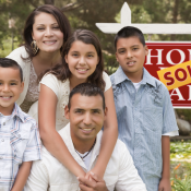 Hispanic family in front of home sale/sold sign