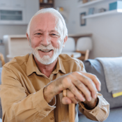 Senior man with a cane sitting on the sofa in his affordable apartment