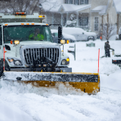 Snow plough clearing street in severe winter weather 