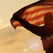 Veteran with unfurled United States flag at sunset