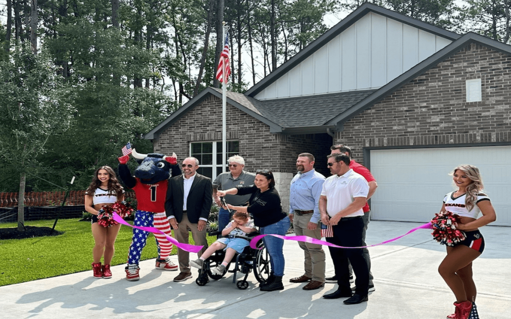 Ellenbeck family, along with homebuilding team, cutting a ribbon in front of newly built home