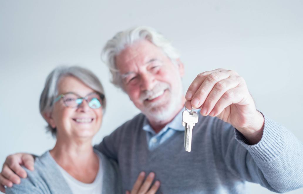 close up of mature man and woman holding a key of a new home