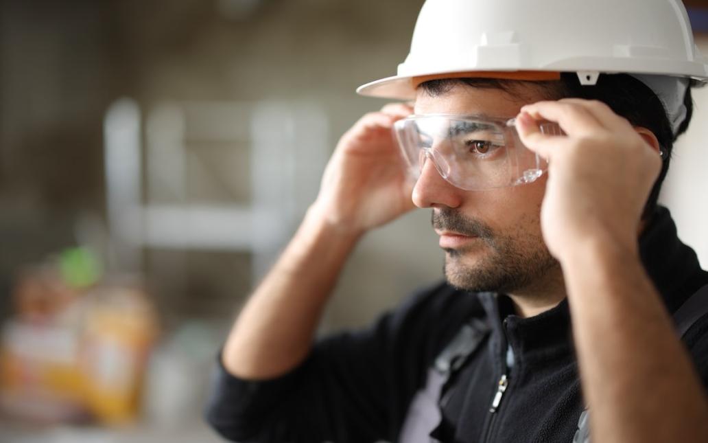 A construction worker puts on safety goggles.