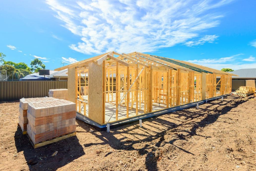 Framing for new home with building materials stacked in foreground