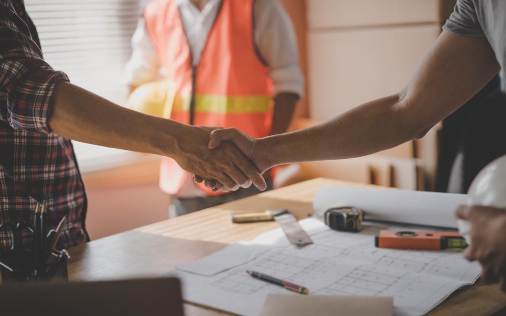 A worker and a homeowner shake hands, negotiating a job.