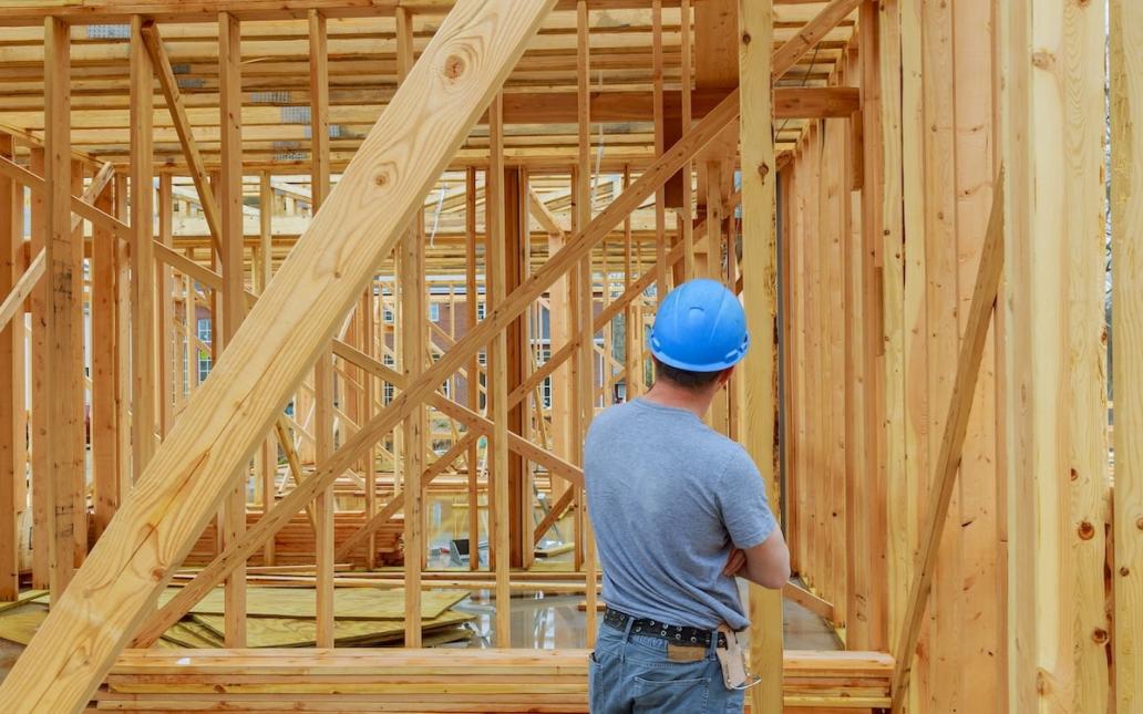 A home builder looks over at framing on new-construction home