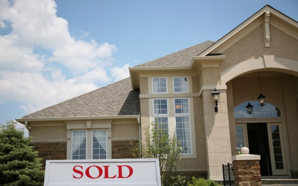 A house with a "sold" sign in the yard