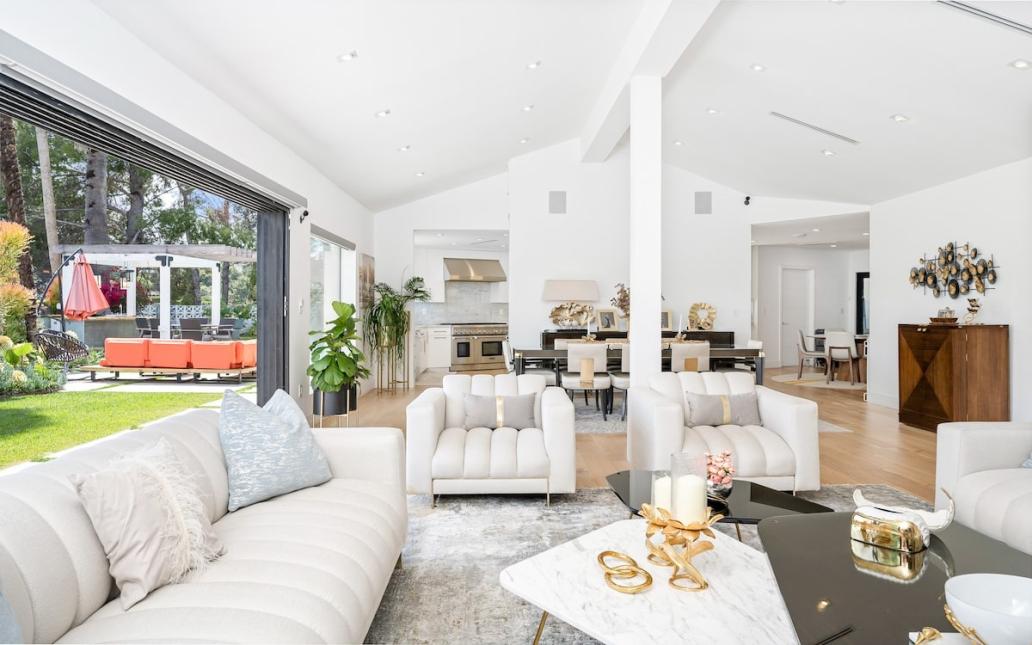 A white room with vaulted ceilings and a large door opening to a backyard