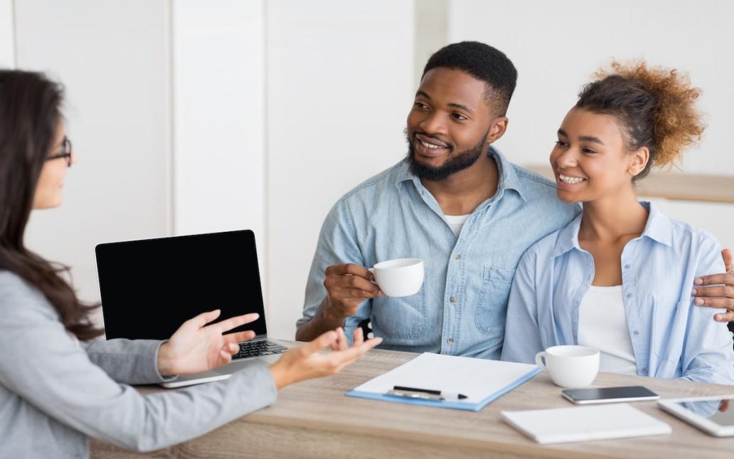 A Millennial couple speaks with a real estate agent about purchasing a home