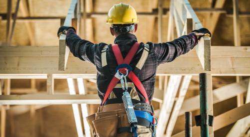 Construction worker standing amid roof trusses in house