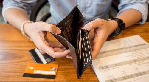 Individual looks through wallet while going over bills