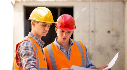 Two Gen Z construction workers go over plans at jobsite