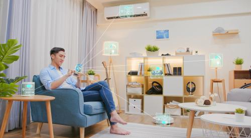 Man sitting in living room using his smartphone for home automation to control his appliances. 
