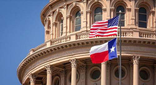 American and Texas flags waving in front of the capitol building in Austin, Texas