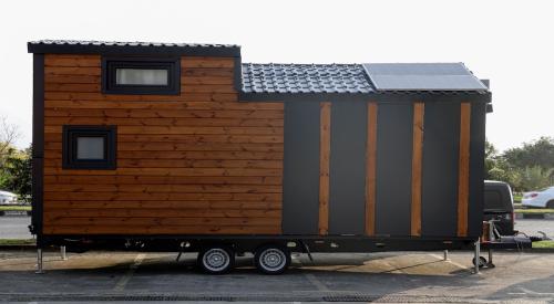 A newly built tiny home sits on trailer in a parking lot ready to be moved to its home