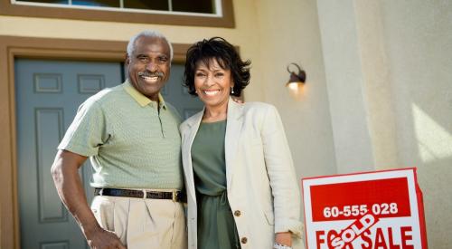 Baby Boomer couple stands in front of recently sold home