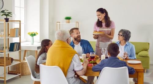 Multi-generational family sits around dinner table enjoying a meal