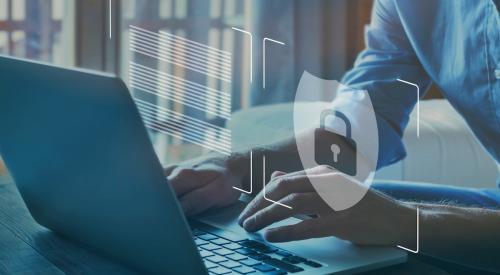 Businessman typing on laptop while padlock symbol floats in front of screen showing the concept of cybersecurity