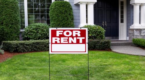 A "For Rent" sign sits in front of a blue single-family home 