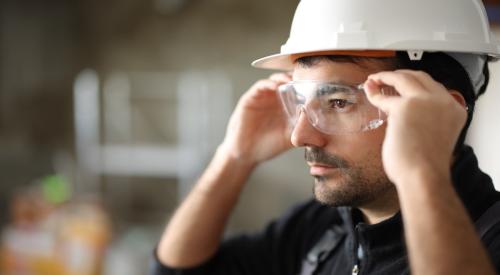 A construction worker puts on safety goggles.