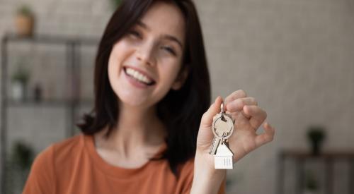 Gen Z woman smiling and holding up house key