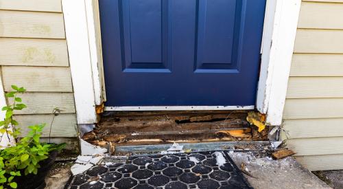 The wooden framing around a doorway is deteriorating