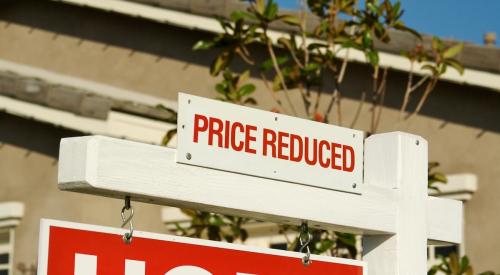 Sign in front of house reading "price reduced"