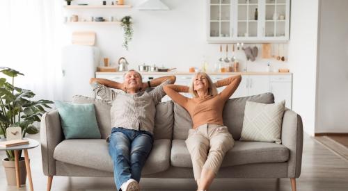 Baby Boomer couple relax and sit back smiling on sofa