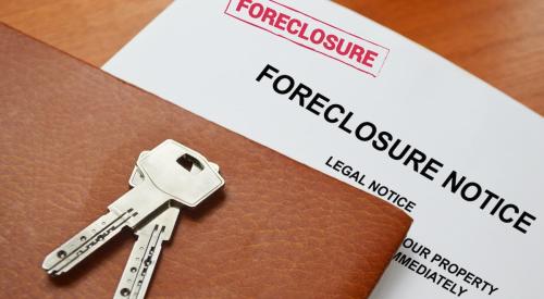 A foreclosure notice with keys on top sit on a table