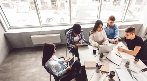 A group of Gen Z coworkers sit around a table working together