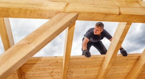 A builder works on the roof of a building