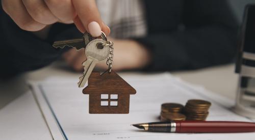 A hand holds up a key above a mortgage loan contract