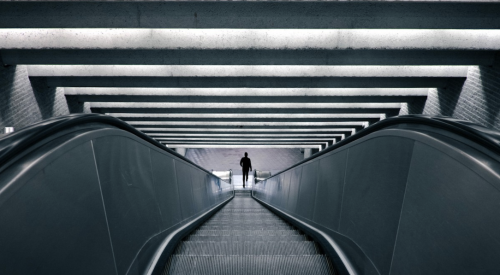 man riding long escalator down to subway