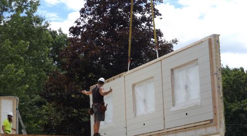 Construction worker installing prefabricated wall panel on jobsite