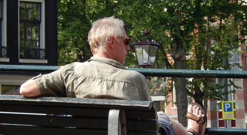 Baby Boomer man sitting on park bench in sun