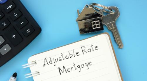 Notepad that says adjustable rate mortgage next to house keys and laptop
