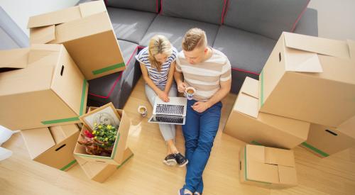 Young couple sitting on floor around moving boxes