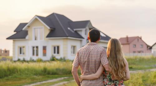 Young homebuyer couple admiring single-family house in a grassy field